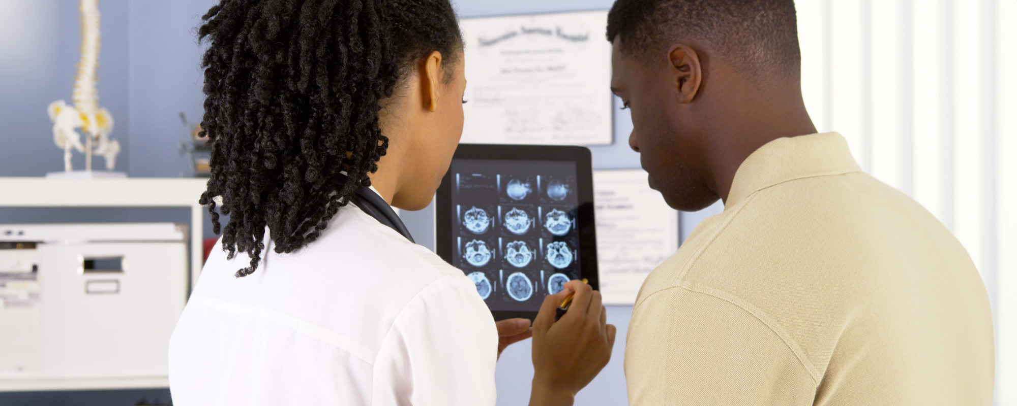 African American doctor talking to patient about brain scans on tablet