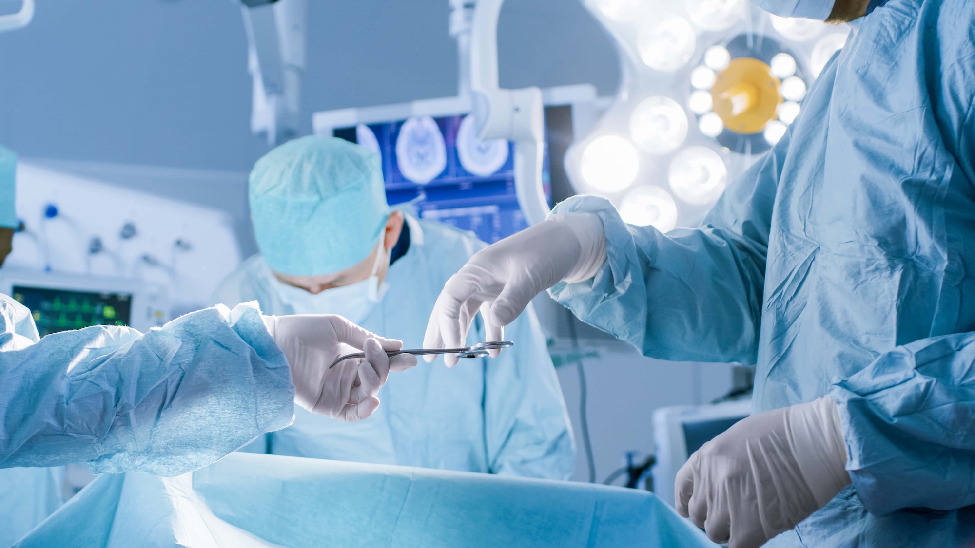 Close up Shot in the Operating Room Assistant Hands out Instruments to Surgeons During Operation