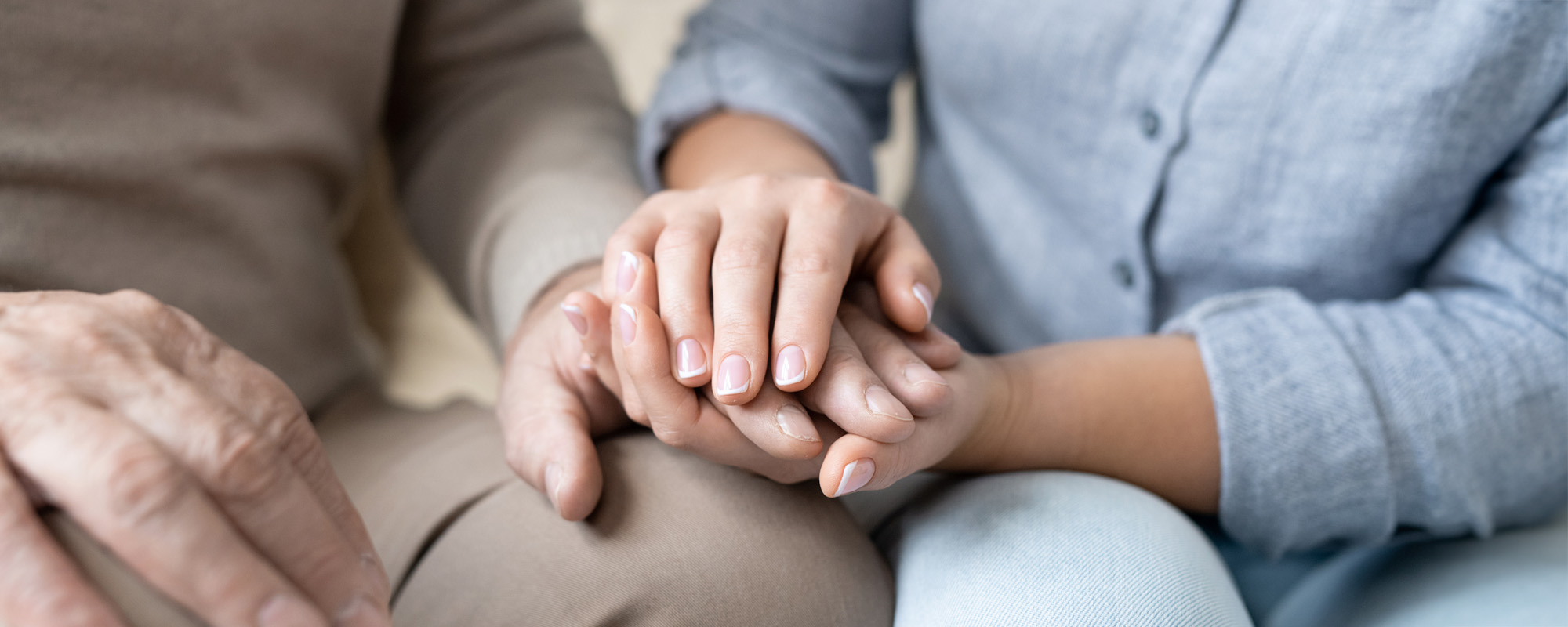 Hand of senior man in casualwear between those of his affectionate daughter