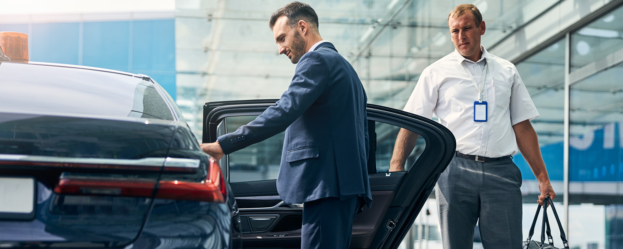 Man in a nice suit opening a car to begin commute from the airport