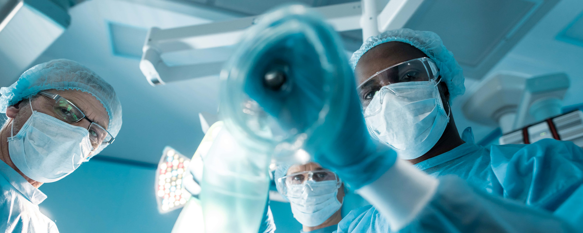 a patients pov on operating table as surgeons look down on patient; Anesthesia Error Lawyer concept image