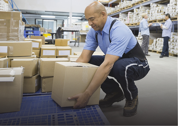 Worker lifting cardboard boxes in warehouse