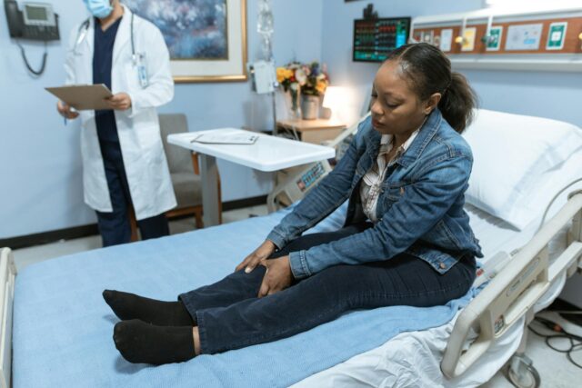woman sitting on bed in hospital holding leg