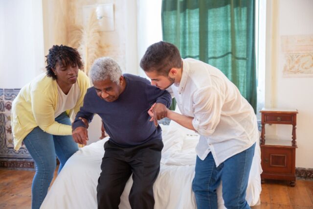 two workers helping man in nursing home